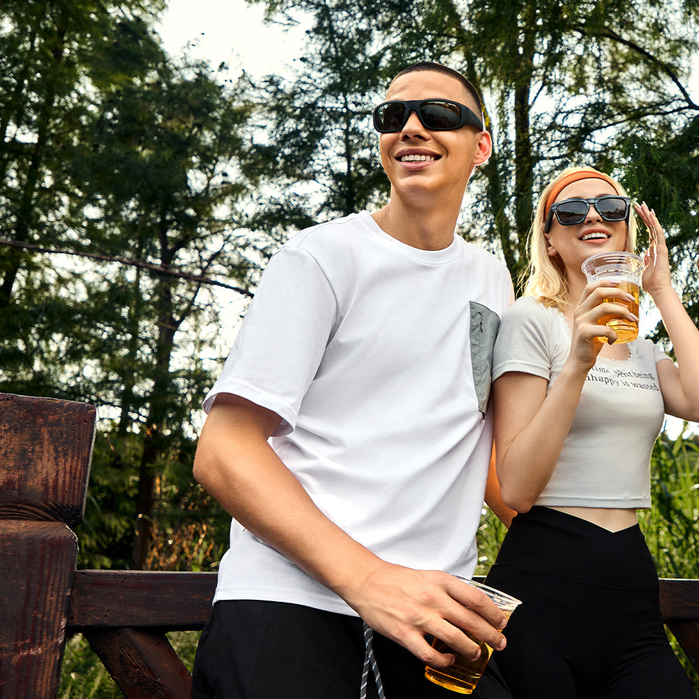 Two people outdoors with drinks wearing OhO Sunshine Pulse polarized Bluetooth sunglasses
