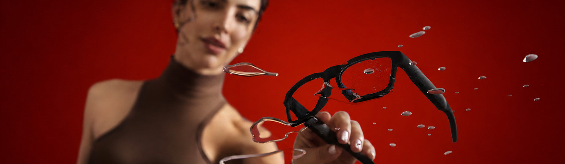 Woman on a red background with new OhO Sunshine smart glasses in a water splash