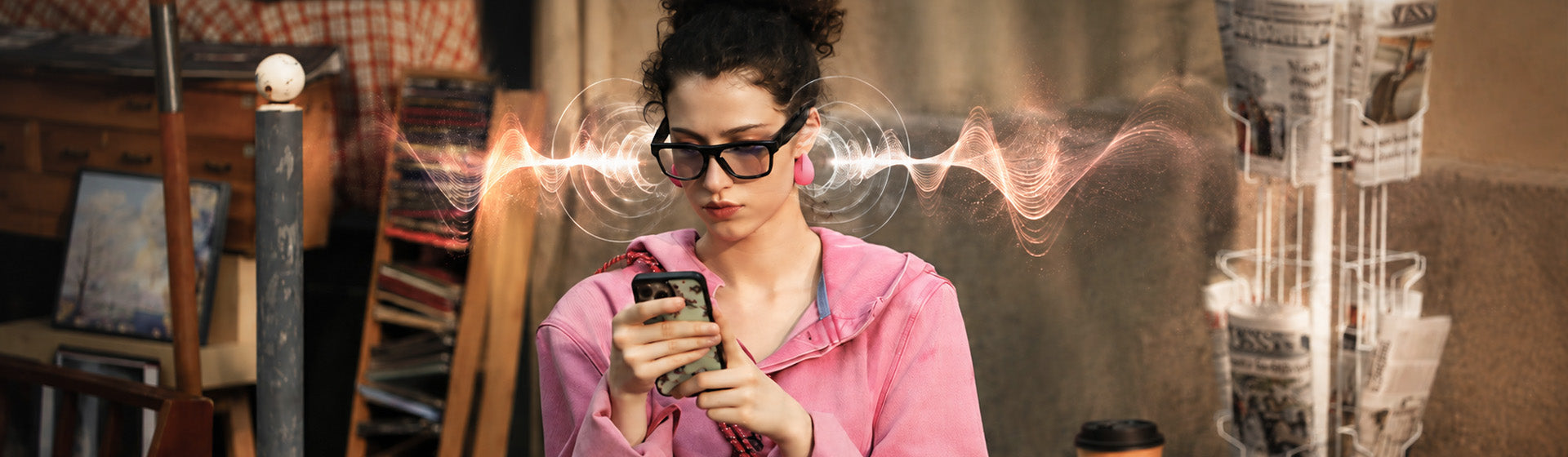 Woman in a pink jacket holding a phone and wearing OhO Sunshine open-ear audio sunglasses
