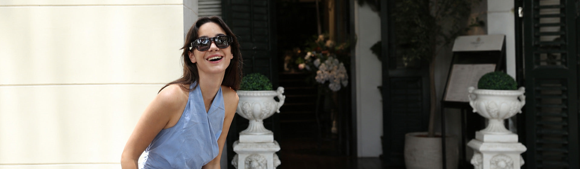 Woman walking past a building wearing OhO Sunshine Touch camera glasses