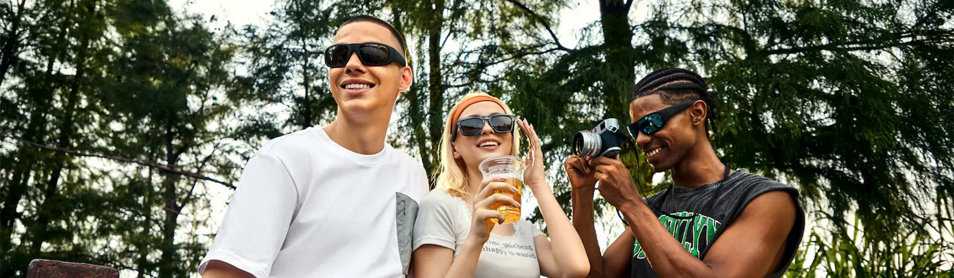 Friends laughing outdoors with drinks while wearing OhO Sunshine Pulse Bluetooth sunglasses