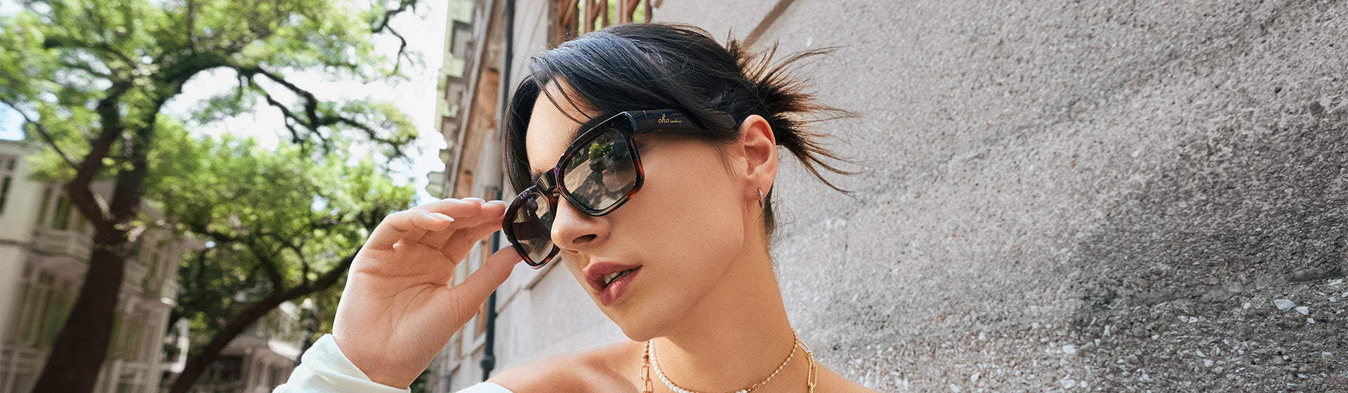 Woman outdoors adjusting OhO Sunshine AI translation sunglasses