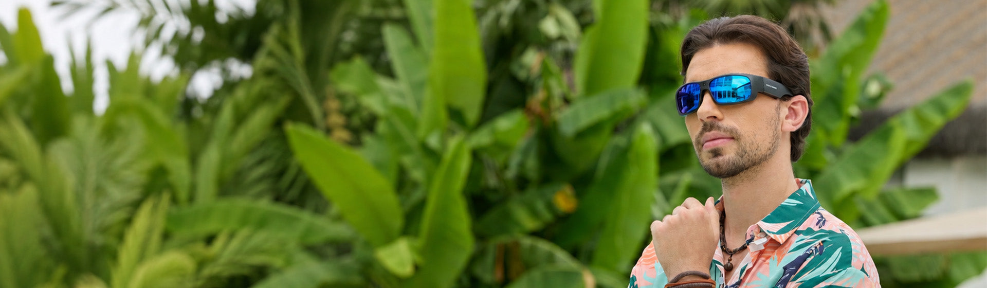 Man in a floral shirt among tropical plants wearing OhO Sunshine Sunblazer Bluetooth sunglasses